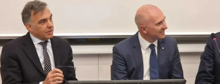 Gregorio Mangano seduto accanto a un'altra persona al convegno della Bocconi